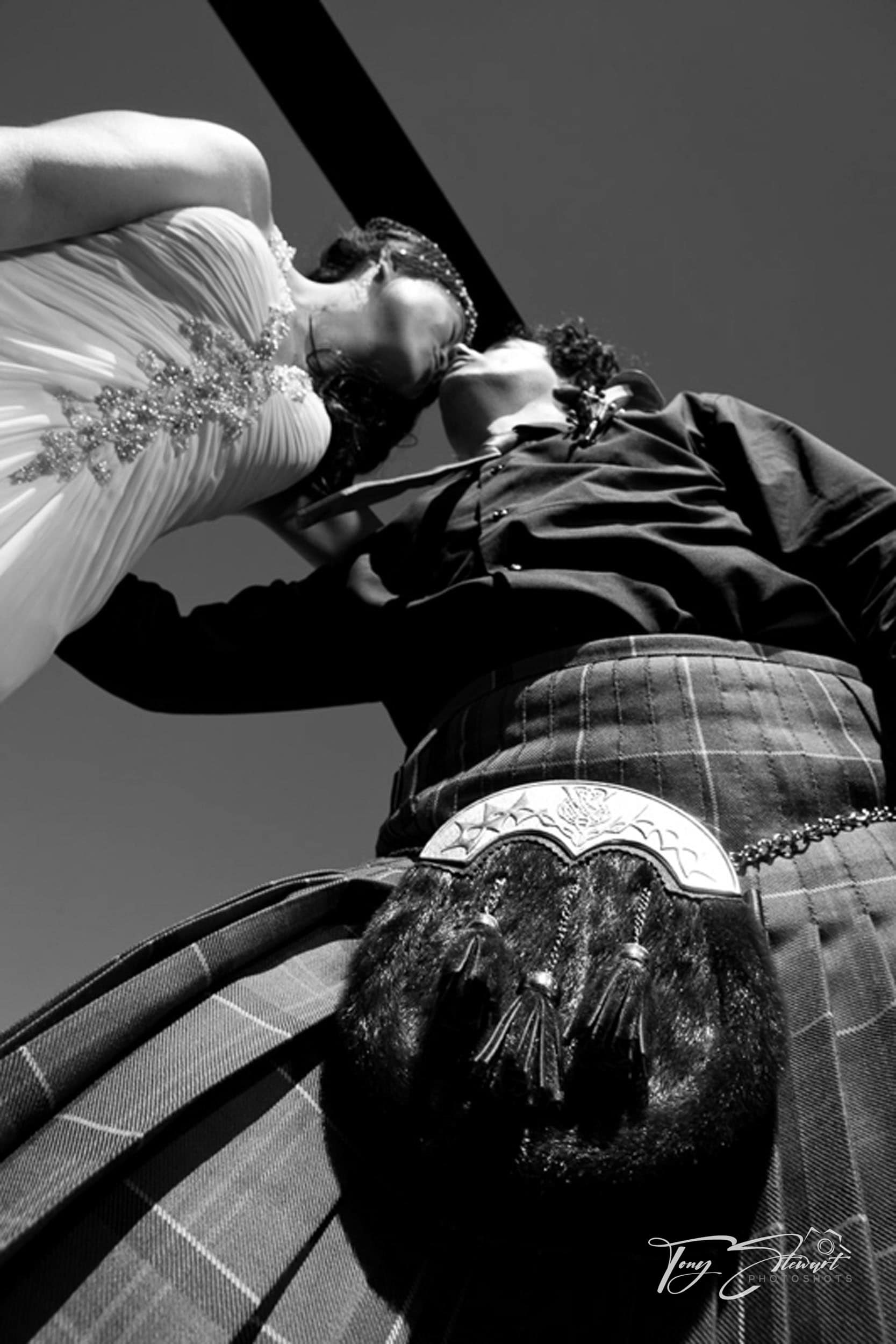 Groom with a scottish kilt kisses his new bride under the rotors of a helicopter, at Terrace Downs, Mid Canterbury.