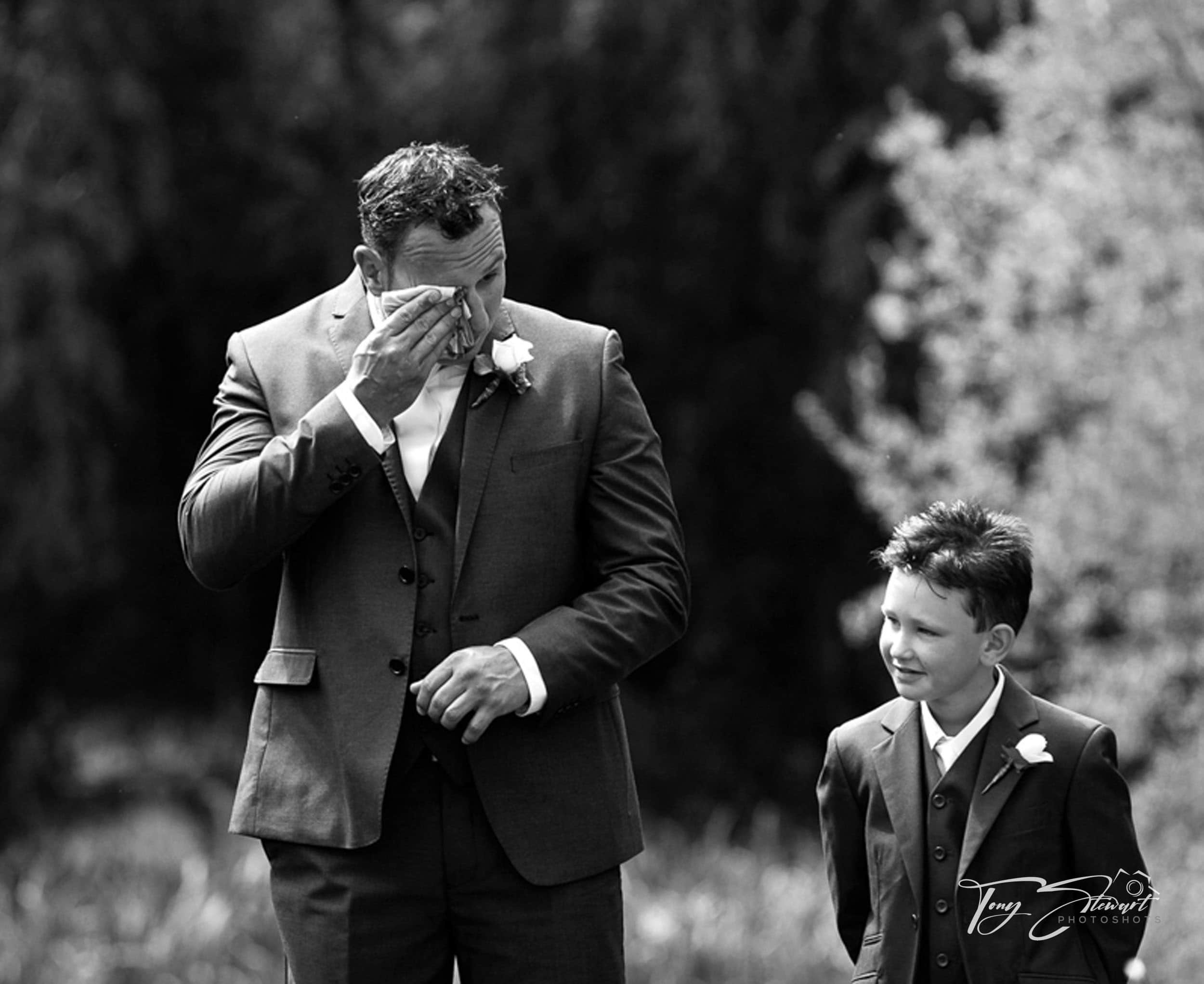 Groom wipes tears during emotional service.