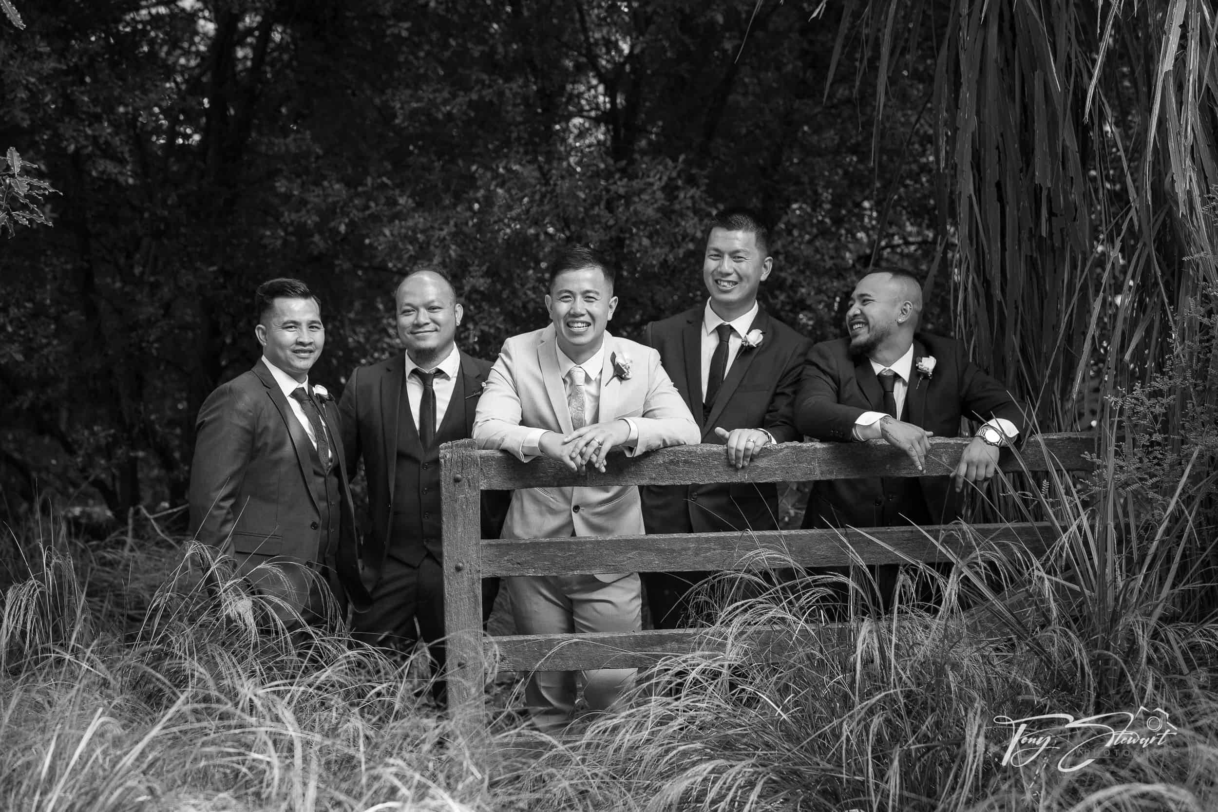Asian groomsmen pose together with groom on rustic gate, Rossendale Estate, Tai Tapu.
