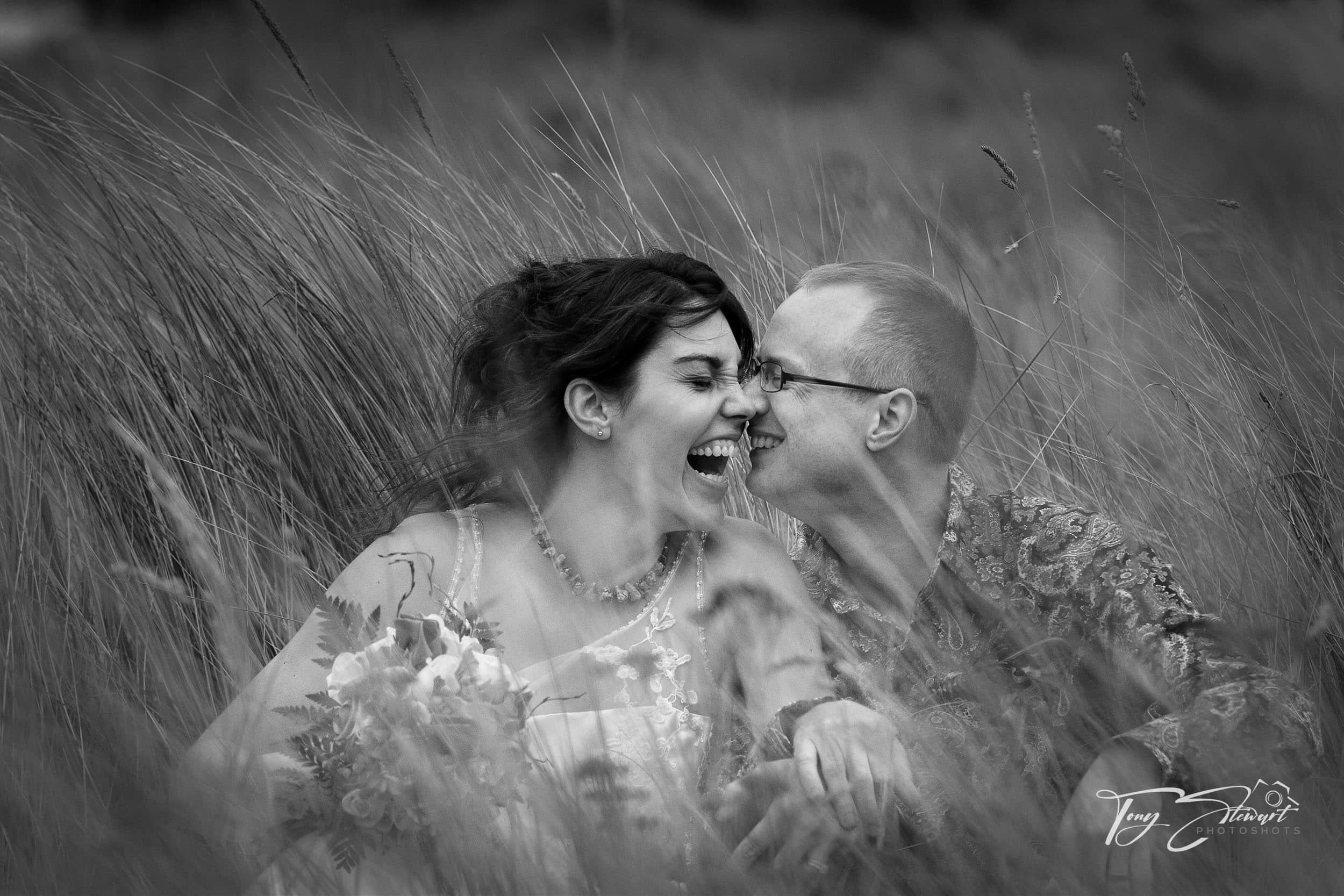 Couple laugh while sitting in long grass, Canterbury.