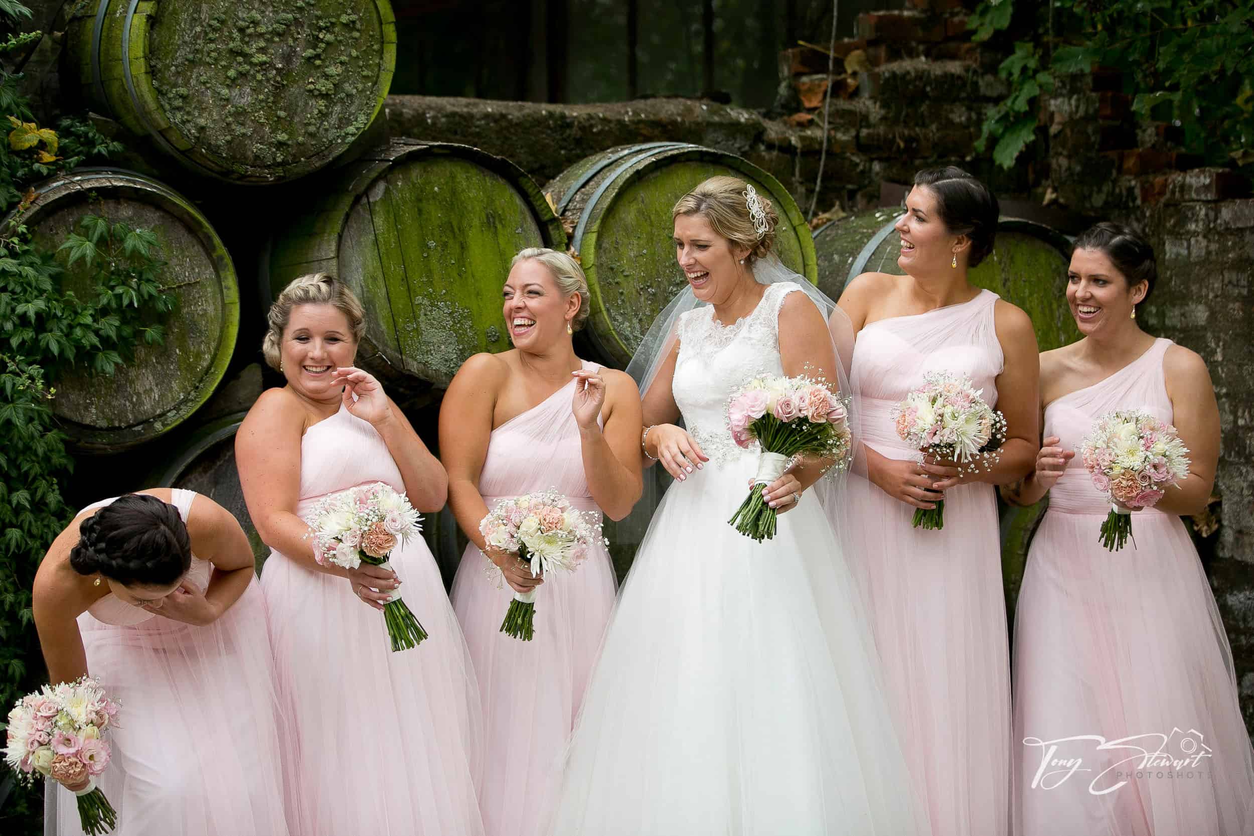 Six girls in a bridal party share a laugh together by wine barrels at Trents Estate.
