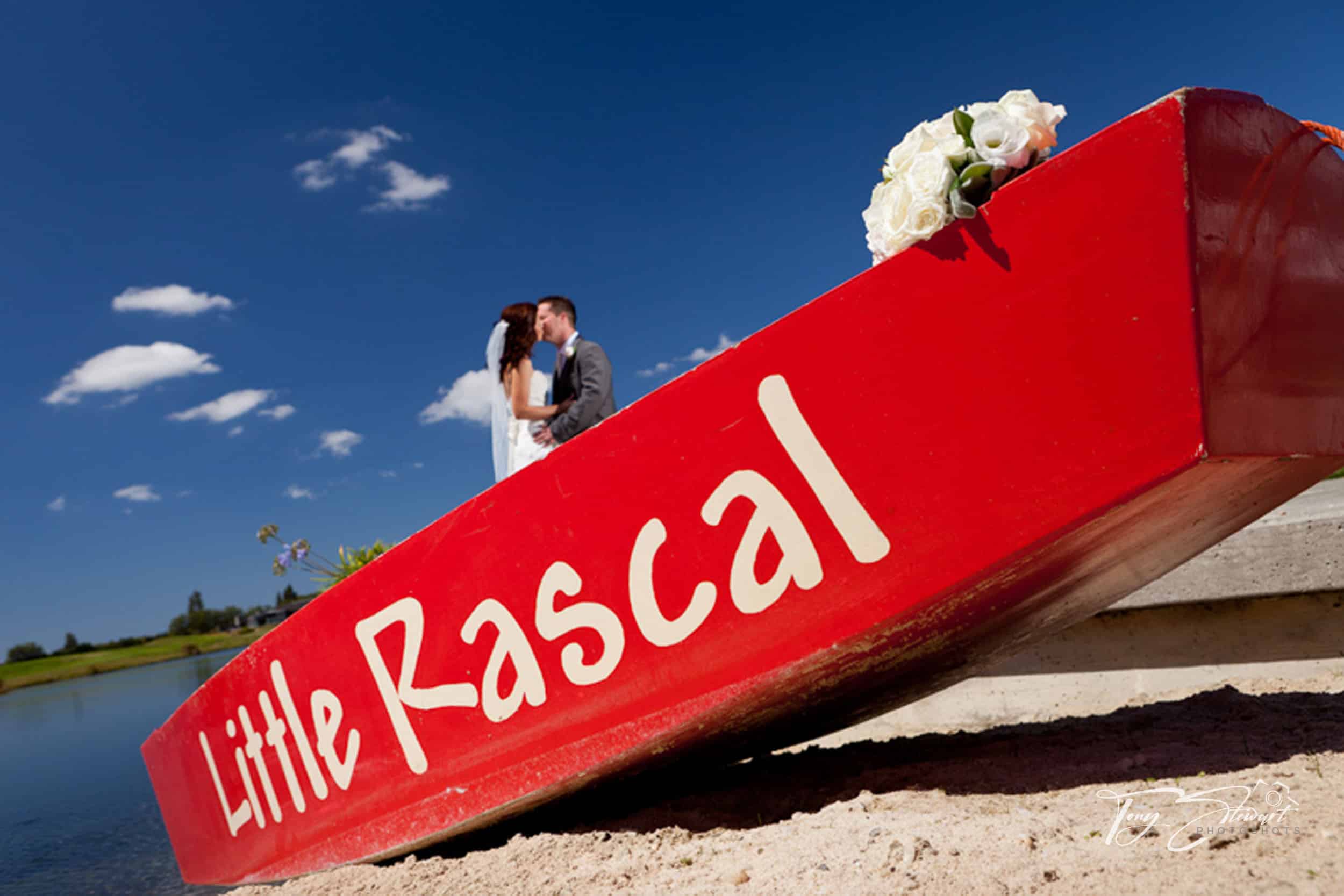 Couple kiss behind dinghy 'Little Rascal' on lake shore, Pegasus.
