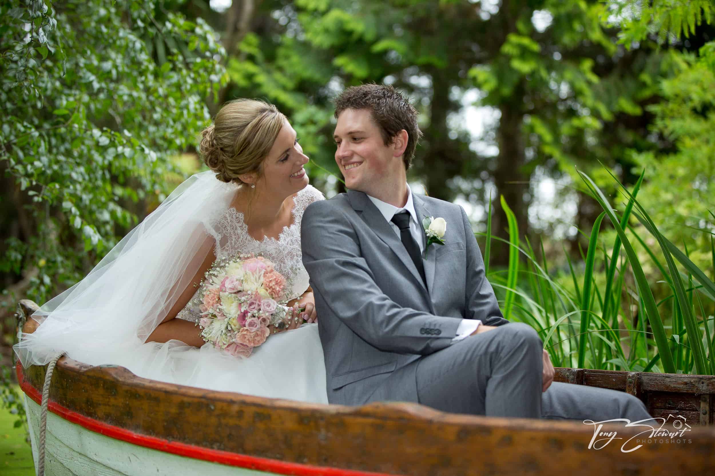 Bridal couple in punt smile before kissing, Trents Estate, Canterbury.